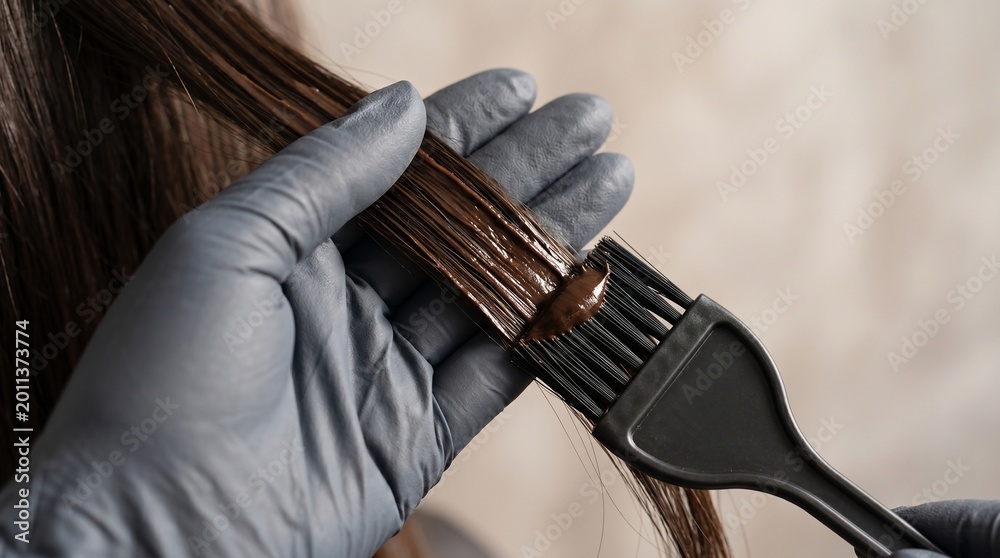 Fototapeta premium Applying hair dye with a brush and gloves for a salon-quality hair coloring experience