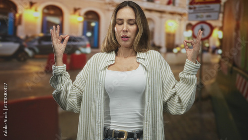 Photography Woman with eyes closed holding hands in prayer and meditative mudra on a busy street near cars and a pedestrian sign; serenity
