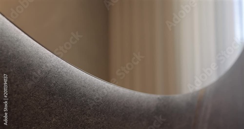 Touchless mirror lighting activation in premium modern washroom, static close shot focuses on the moment a hand reaches under rounded edge and delicate glow appears against the textured stone surface