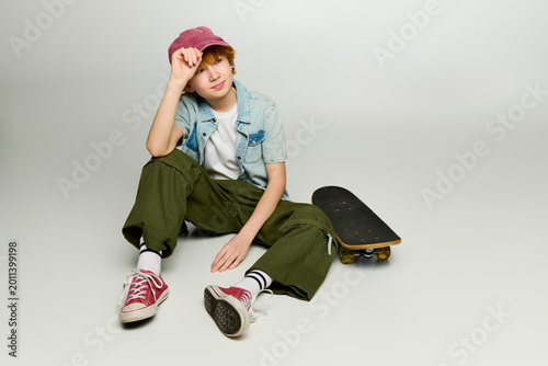 Fotografija Stylish kid showcasing vibrant fashion with skateboard in a modern setting