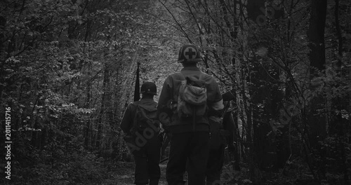 squad of Soviet military men and US soldiers walk through a green forest during World War II in historical uniforms
