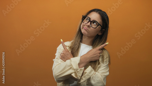 Fotografija Woman crossing arms and pointing fingers showing yellow nails in studio with orange backdrop; defiance