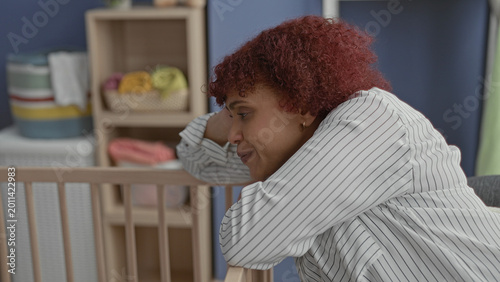 Foto Woman leans on crib rail holding her head in a building nursery, gazing down toward the cot; maternal fatigue