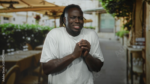 Foto Man with hands raised palms out and squinting face on restaurant terrace showing expressive gestures; awkwardness