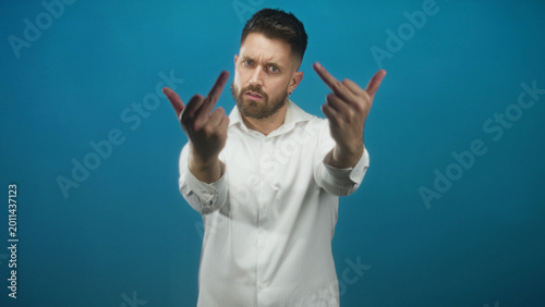Cuadro en lienzo Man in white shirt extends hands and shows middle fingers toward camera in studio; defiance provocation