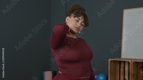 Foto Woman massaging neck and stretching shoulder in studio with yoga mat and exercise balls; relief recovery wellness