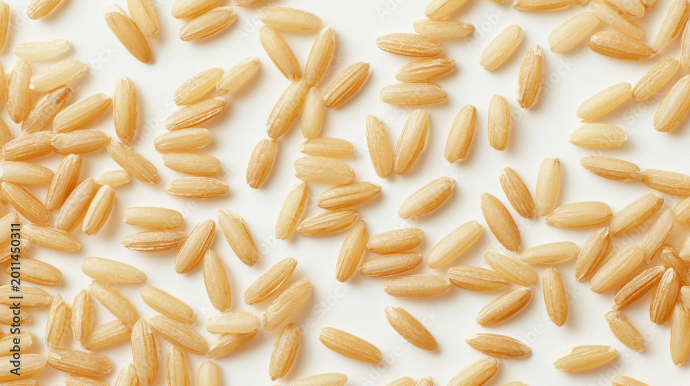 Obraz premium Top view of uncooked brown rice grains evenly spread on white background, clean minimal composition, soft natural lighting, subtle shadows concept for digital content