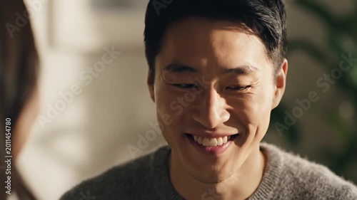 Close up Potrait of a Happy Smiling Asian Man in Gray Sweater having Conversation in Sunlit Indoor Background