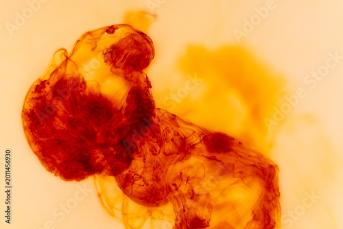 Abstract red and orange ink clouds dissolving in liquid, creating organic flowing shapes and textures