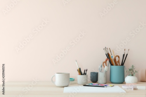 Minimal desk with art supplies arranged in clean modern layout under soft studio lighting
