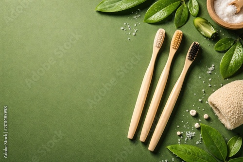 Natural bamboo toothbrushes placed on green background seen from above with copy space promoting eco products