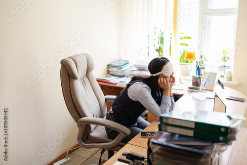 Fényképezés Business woman in a mask blindfolded asleep in the office