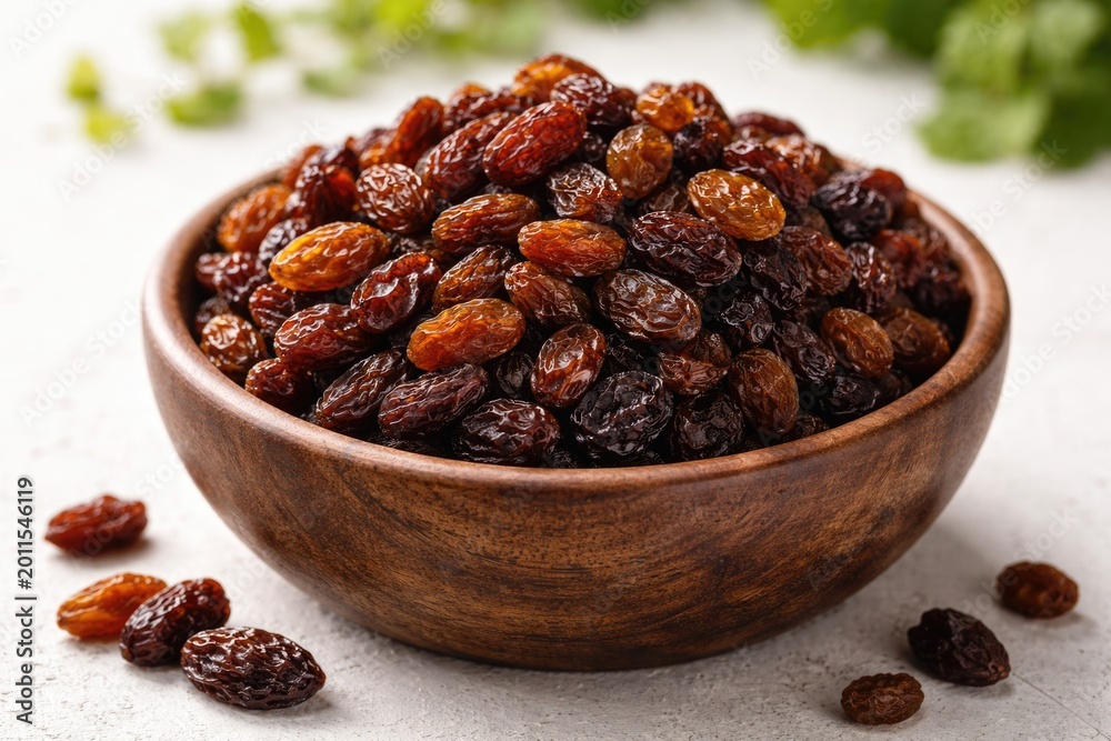 Obraz premium Dried grape raisins presented in an artisan wooden bowl with white background