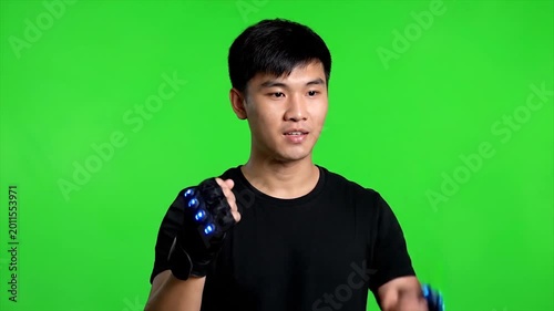 Young man gestures towards camera with hand extended in front of green screen