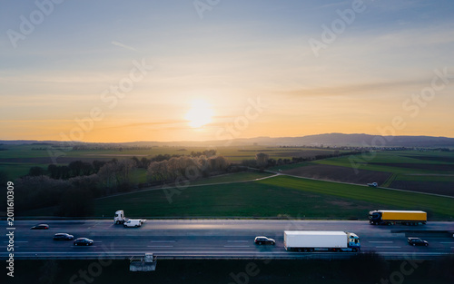 Aerial side view of a highway with transport trucks at sunset