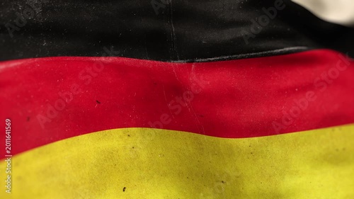 A Germany flag, made of old cloth, dirty and stained, flutters in the wind. A Worn German Flag Waves In The Breeze.