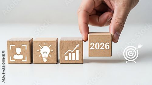 Hand placing a wooden block with the year 2026 to represent future business growth strategy goals