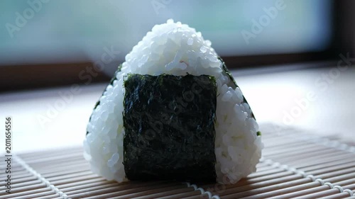 Triangular onigiri rice ball with nori seaweed wrapper, traditional Japanese snack, soft focus background with steam rising