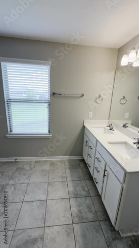 Empty vacant renovated house bathroom with a window and white cabinets and granite countertop vanity with tile floor.