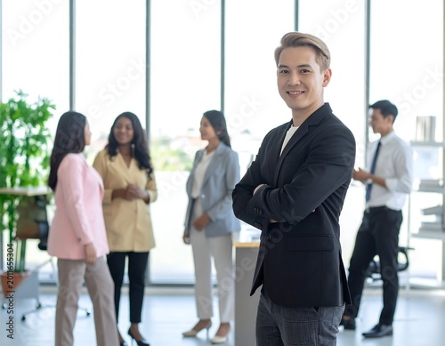 Confident Young Businessman Standing with Crossed Arms in Modern Office