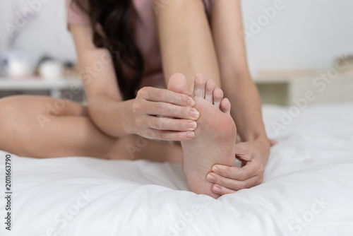 Obraz na płótnie Young asian woman on bed feeling foot pain and discomfort