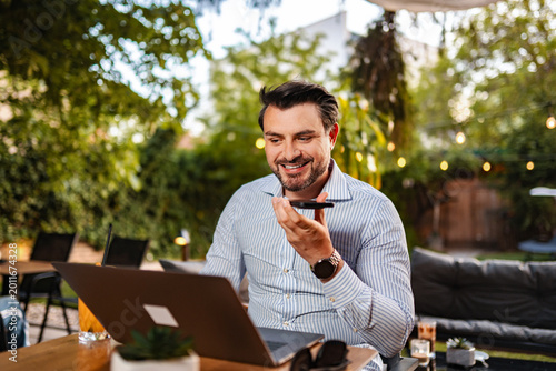 Cuadro en lienzo Man dictating voice message using phone outdoors with laptop