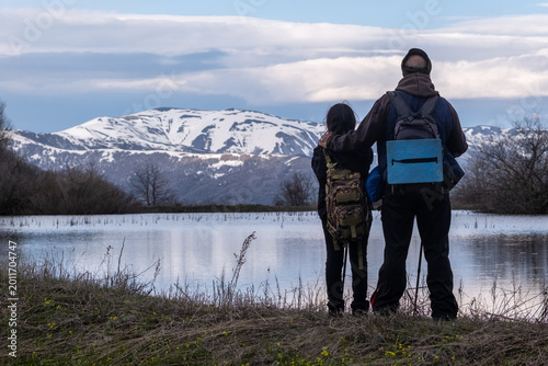 Billede på lærred Father and daughter admire lake with glacial water and scenic mountains with snowy peaks
