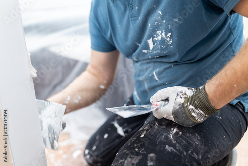 Foto Close Up of Plasterer Holding Putty Knives During Wall Repair