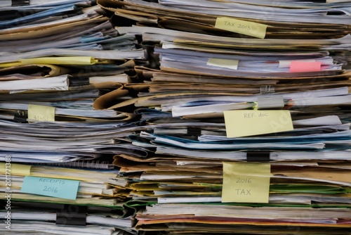 Massive stack of messy office paperwork and tax documents with sticky notes