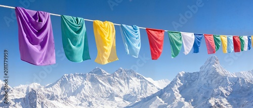 Colorful prayer flags flutter against snowy mountain peaks