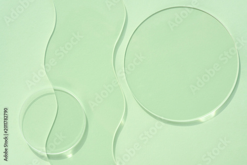 Transparent glass discs on pastel green background. Spa concept. Top view with space for text