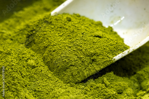 Ceremonial Matcha Green Tea Powder in White Scoop Over Bowl Close-Up for Culinary Use