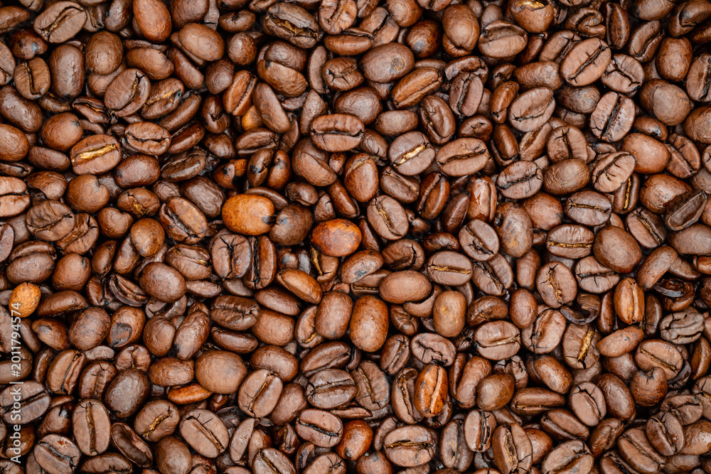Fototapeta premium Many coffee beans are spread out on a flat surface showing different shades and textures throughout the scene
