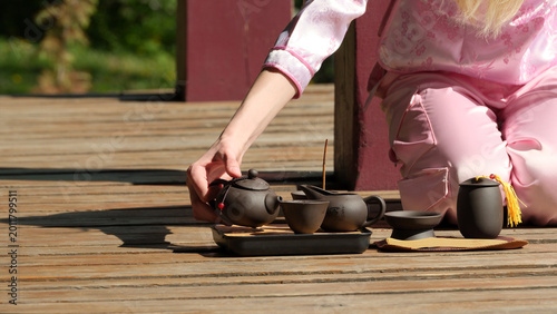 Delicate tea ceremony unfolds on a sunlit wooden deck