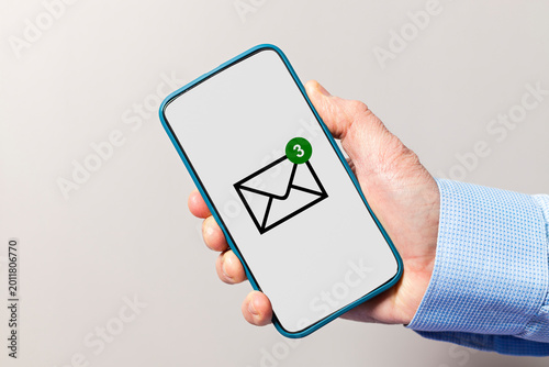 Hand holding smartphone showing email message notification