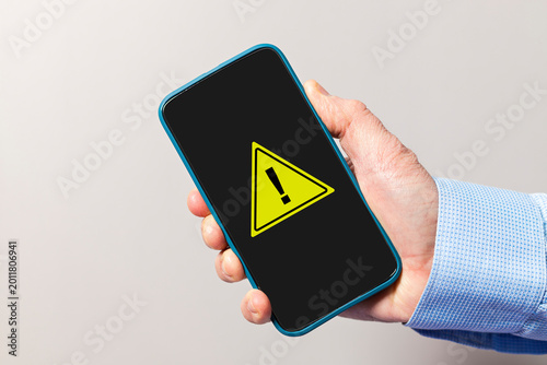 Hand holding smartphone displaying warning security alert sign