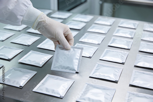 Fotografía Gloved hand arranging sealed foil packets on a sterile laboratory surface