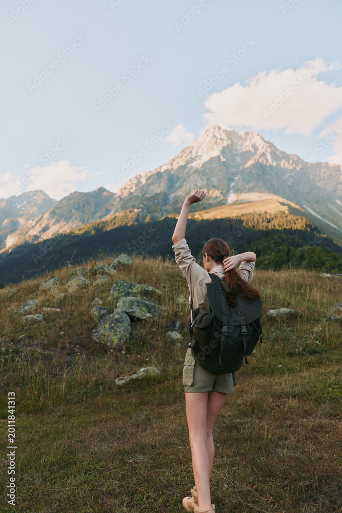 Naklejka premium Woman hiker with backpack traverses a mountain trail, enjoying outdoors, expansive landscape, clear sky, sense of adventure and freedom in nature, travel lifestyle, photography moment