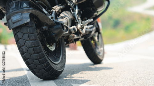 Foto Close-up of a motorcycle rear wheel on a sunlit road, highlighting the tire tread and mechanical details