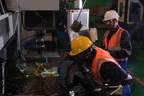 Foto Workers perform machining tasks in a workshop using CNC machine and monitoring w