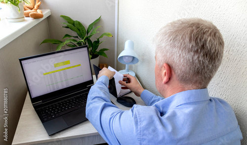 Tableau sur toile Man studying numbers on the laptop screen on the modern desk showing spreadsheet with loan amortization table