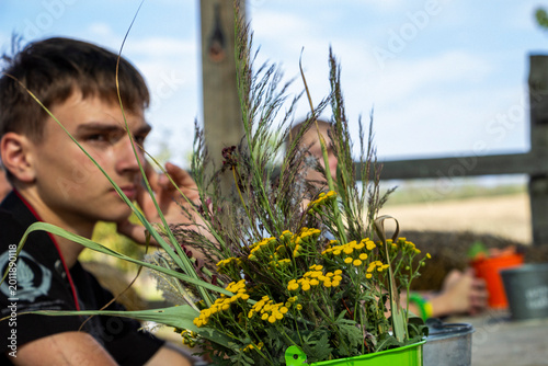 Cuadro en lienzo teenage boy sits behind a bouquet of tansy and herbaceous field plants in an ope