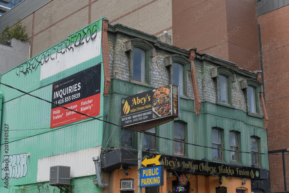 Fototapeta premium exterior of historic building and sign of Abey's Indian Chinese Hakka Fusion, a restaurant, located at 118 John St, Toronto