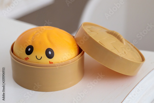 Tableau sur toile yellow kawaii squishy dumpling toy with smiley face sitting inside open plastic