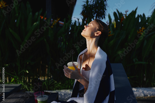 Canvas Print Outdoor sun relaxation and leisure in a garden setting, a person with a towel draped over shoulders enjoys a beverage, creating a casual lifestyle moment of summer calm and well being
