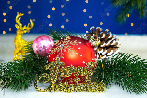 A large red ball with letters near Christmas tree branches with a pine cone and a deer