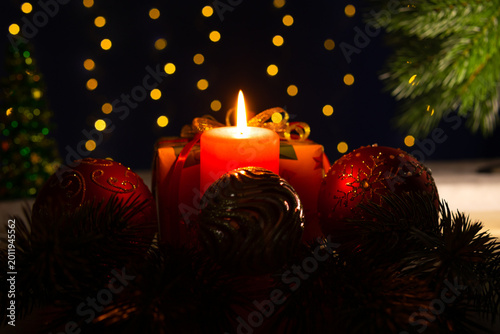 Between two large balls there is a burning candle with a gift