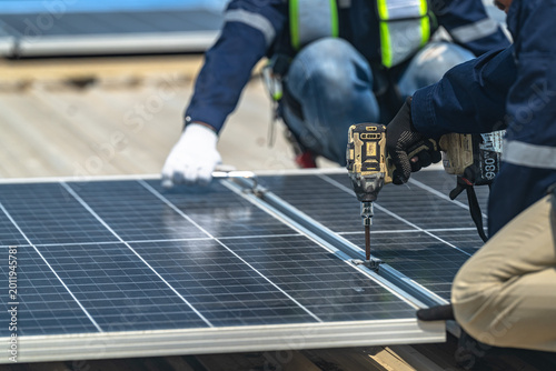 Konstfotografi Detailed view of an installer's hands in protective gloves tightening bolts on a solar panel frame using a specialized wrench