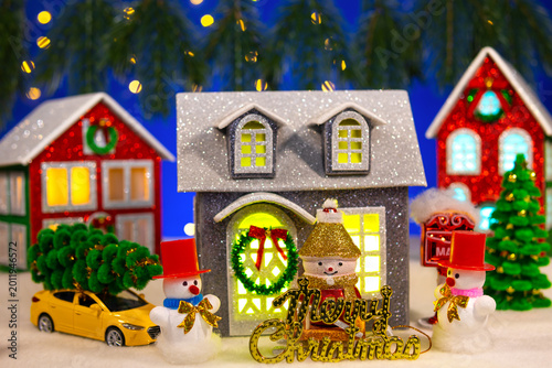 In front of the two houses there is a grey house with letters and snowmen