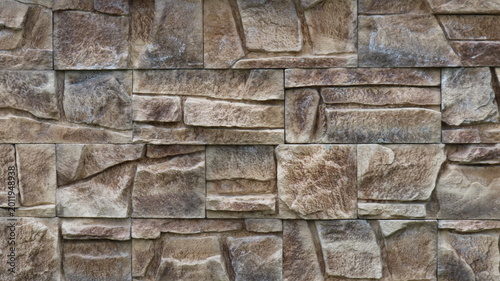 Foto wall finished with square stone tiles of various sizes in a gray-brown color wit
